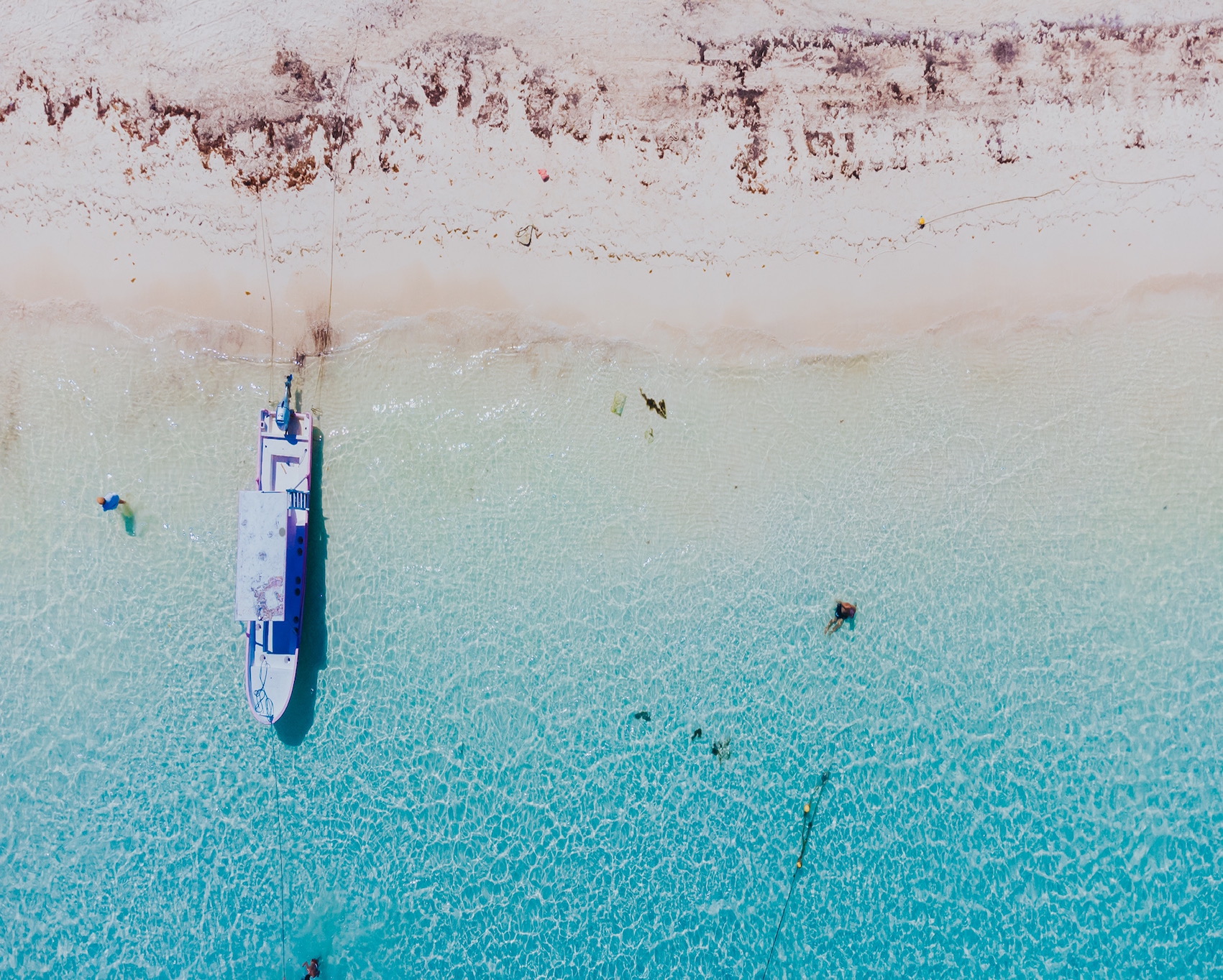 Aerial view of a fishing boat on the powder-white shore and turquoise shallows of Puerto Morelos